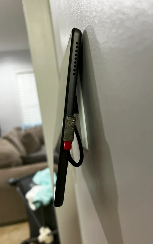 Side profile of the tablet hanging on the magnet, leaning off the wall